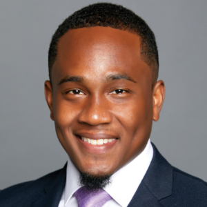 Professional portrait of a man named Jean-Dominique Foureau, with a beaming smile, wearing a navy suit and a lavender tie.