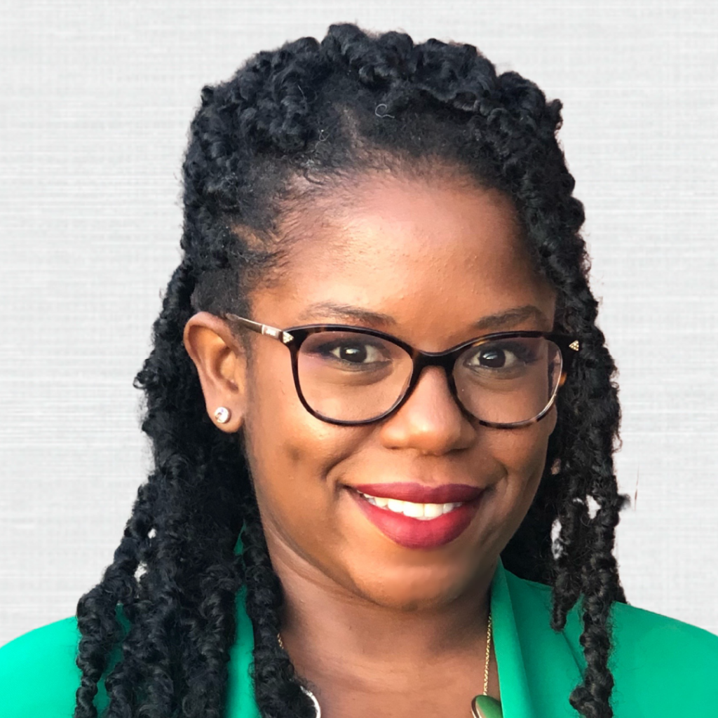 Portrait of Dr. Christine Sainvil, a woman with glasses, wearing a green jacket, and smiling with braided hair.