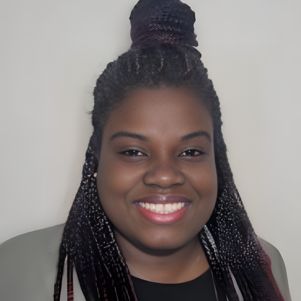 Portrait of Rhenie Dalger, a smiling woman with braided hair styled in a high bun, wearing a dark top and a light-colored jacket.